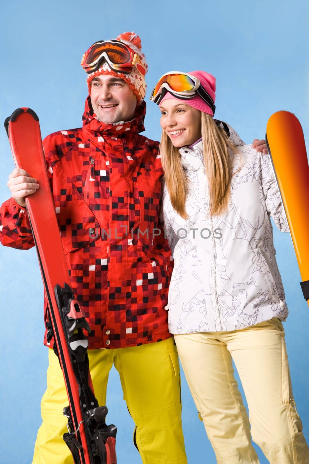 Portrait of happy couple with skis in hands looking aside with smiles
