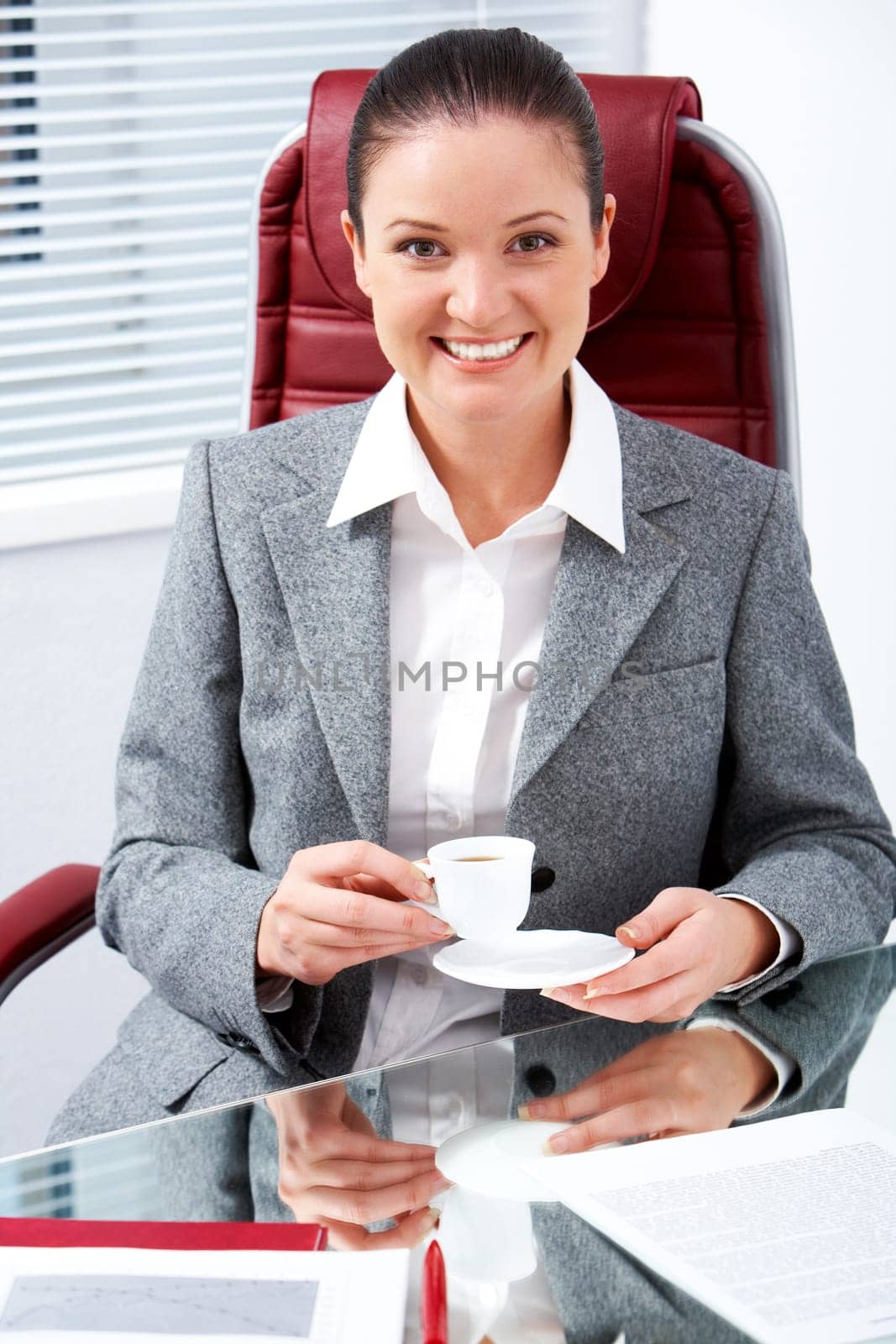 Portrait of happy professional with cup in hand looking at camera with smile in office