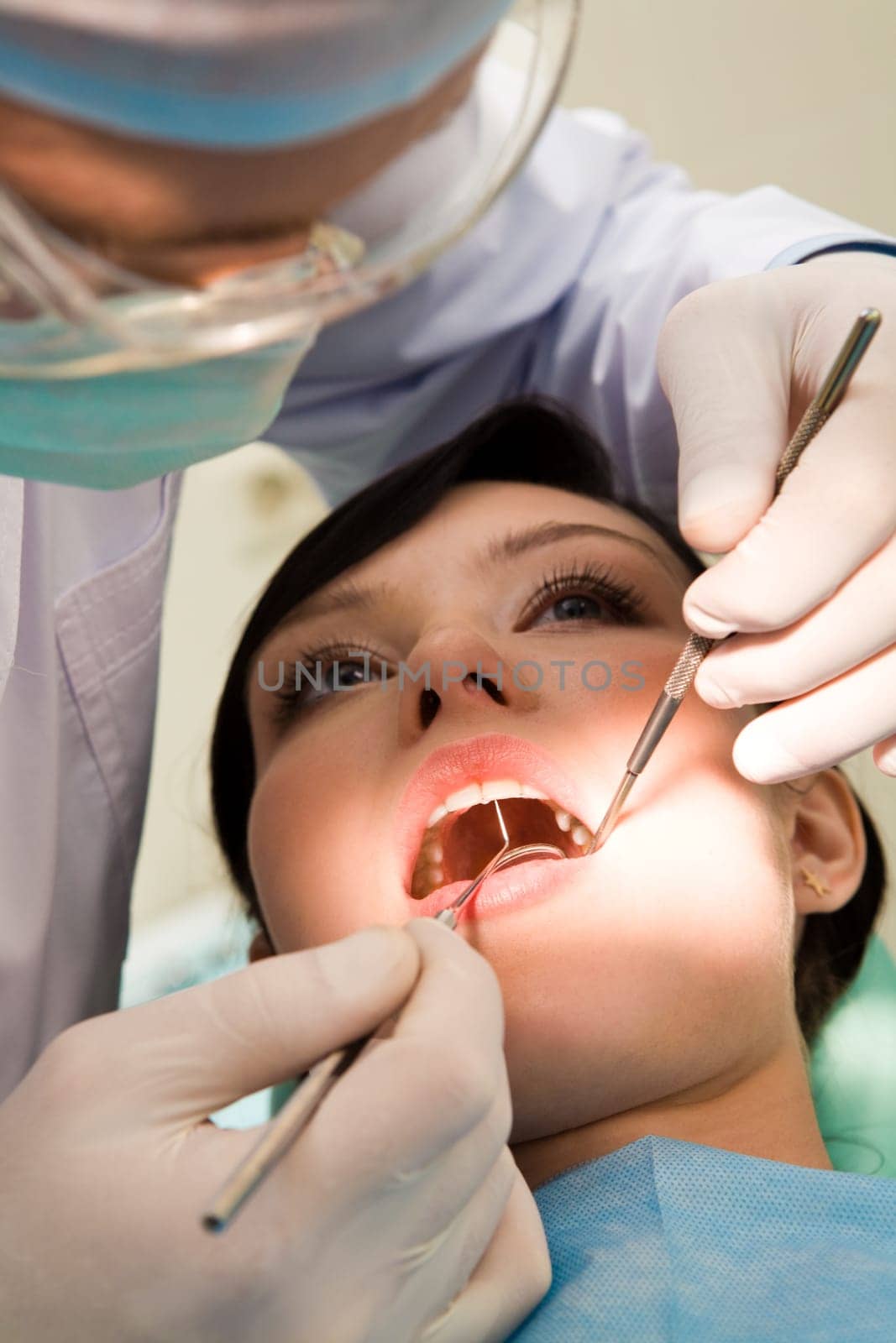 Close-up of woman with open mouth being examined by hygienist