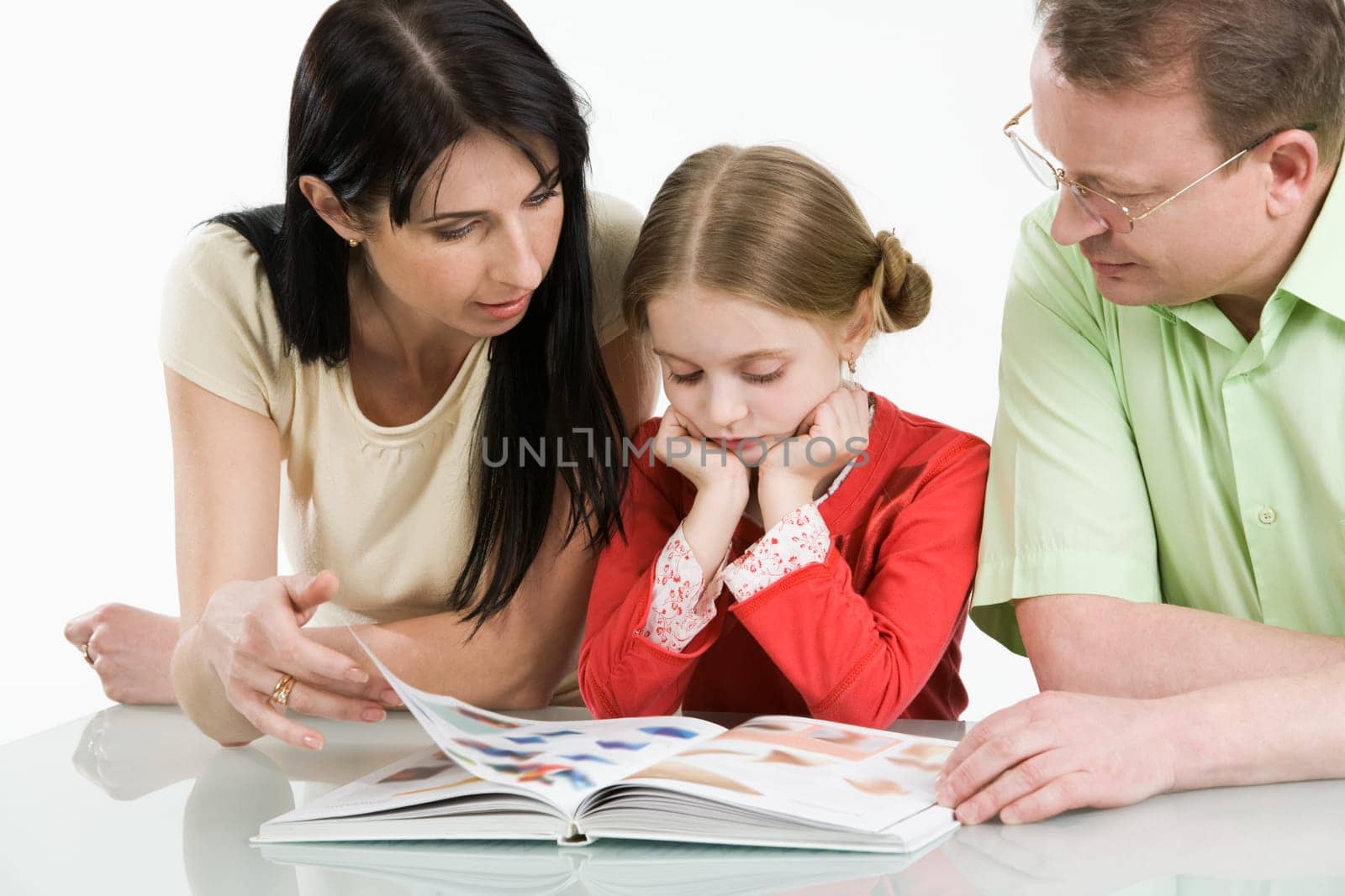 Image of father, mother and their daughter looking through interesting book together