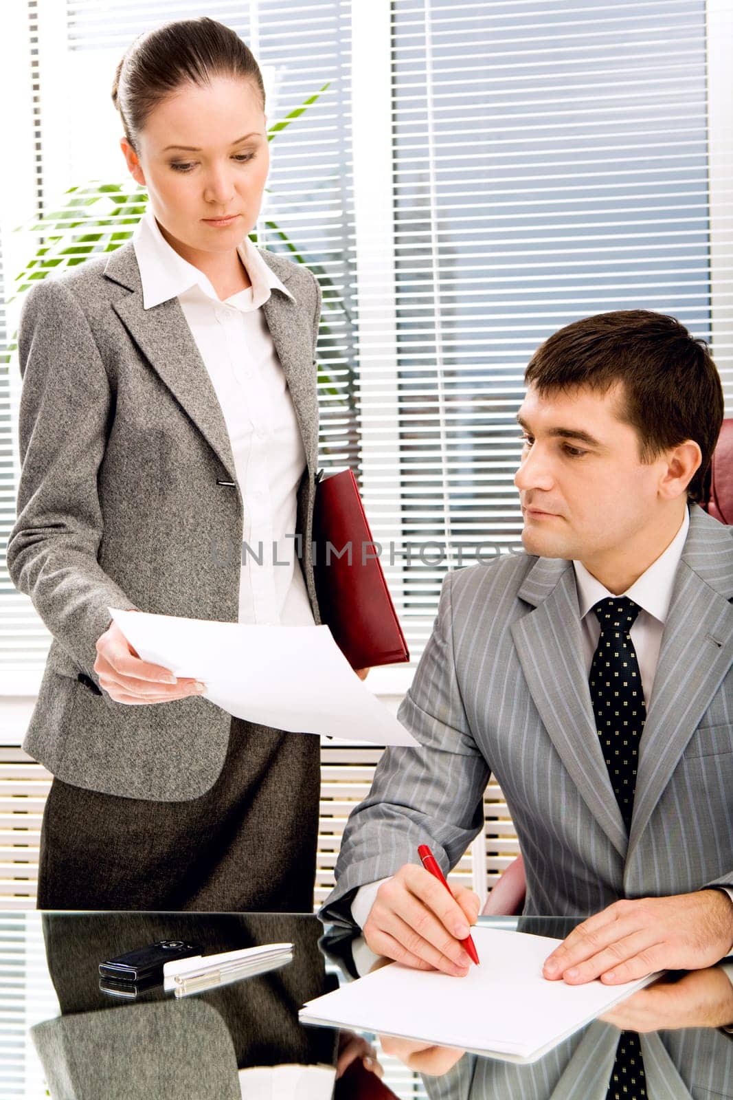 Photo of confident leader looking at documents being shown by his secretary