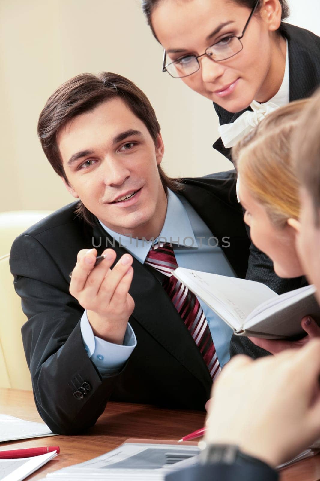 Portrait of handsome businessman explaining something to his colleagues with smart woman near by