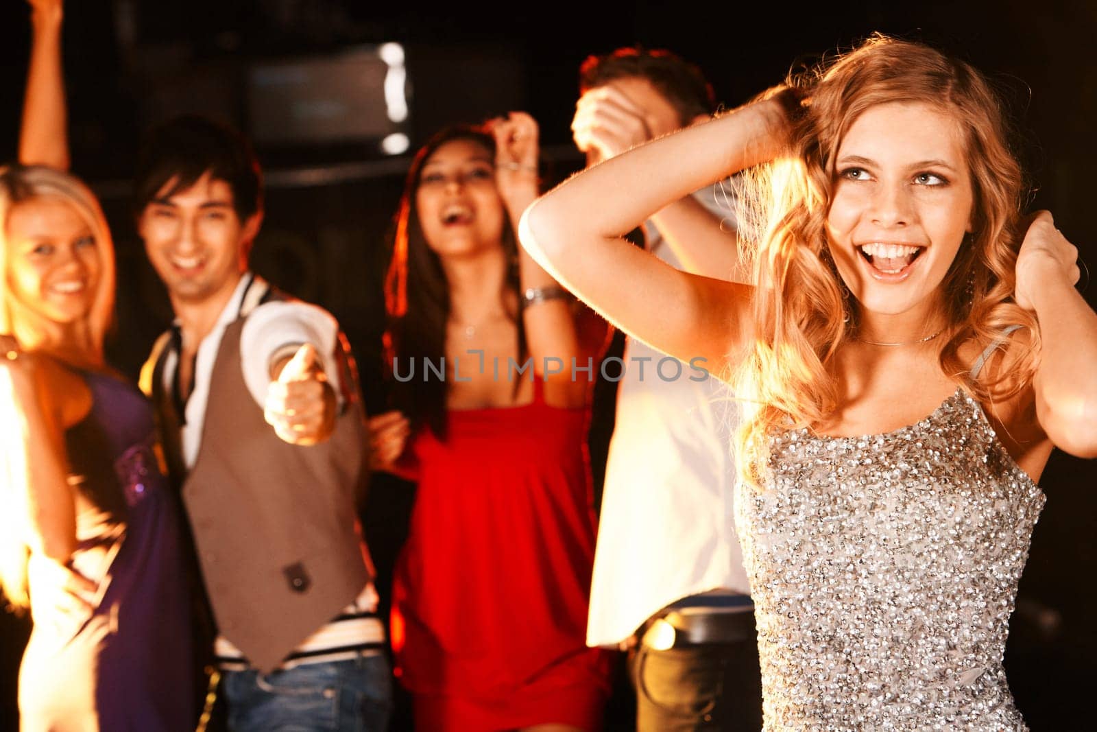 Portrait of joyous girl dancing at party with her friends behind
