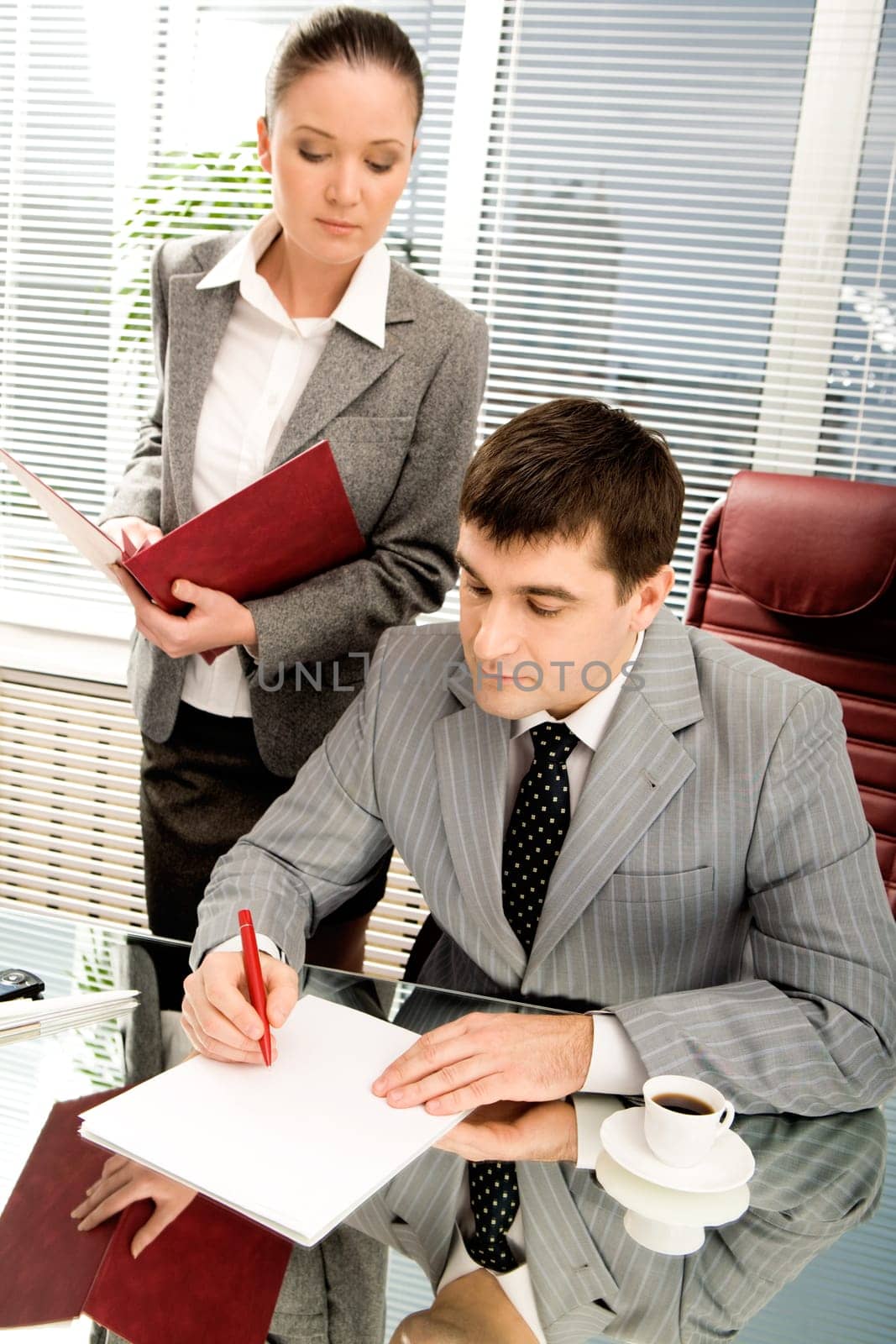 Portrait of serious boss going to sign contract while executive secretary standing near by