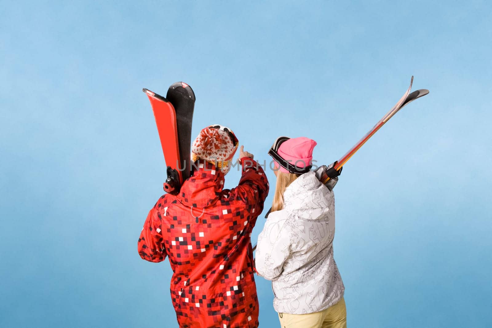 Back view of sporty couple pointing at something over blue background