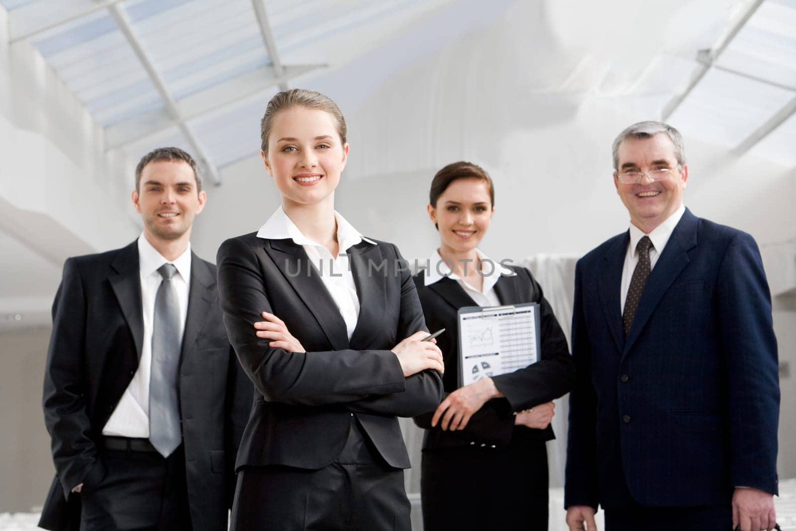 Portrait of smart businesswoman looking at camera at background of co-workers