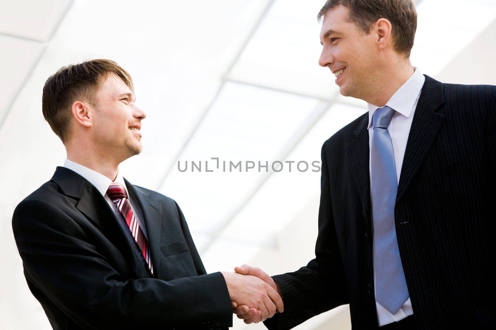 Portrait of two happy businessmen handshaking after striking promising deal