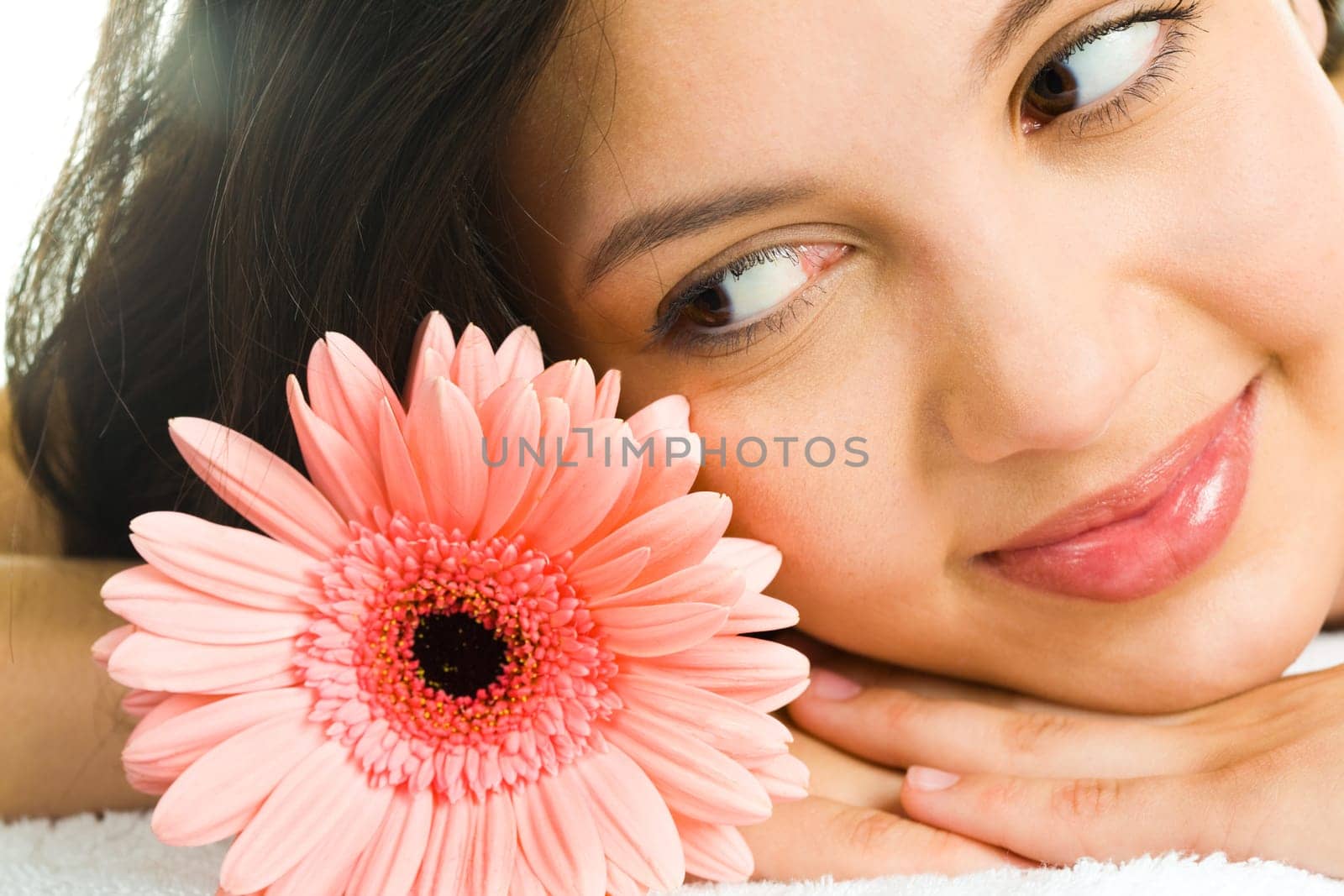 Close-up of young brunette looking at a pink daisy