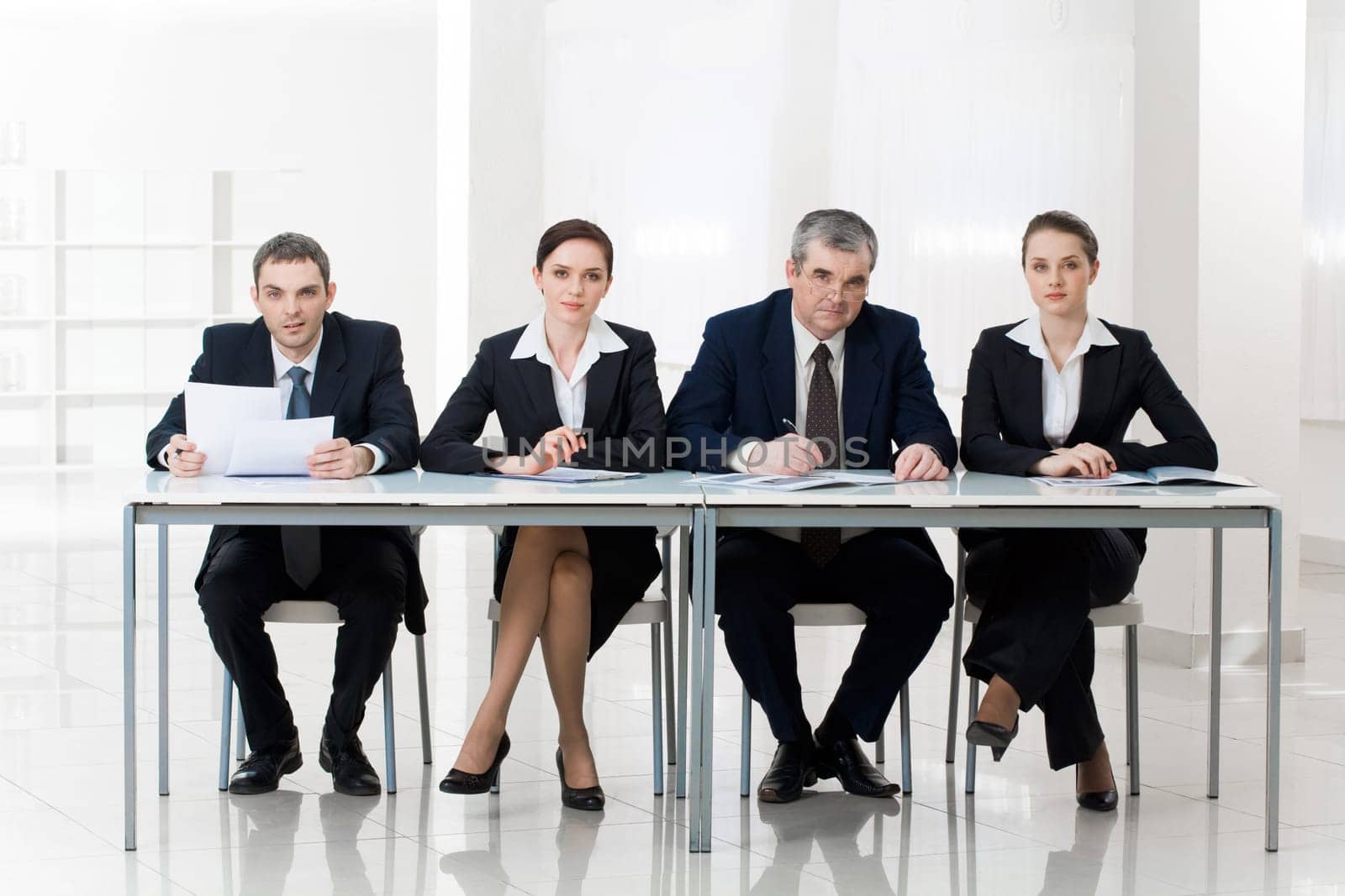 Portrait of smart business people sitting at table and looking at camera