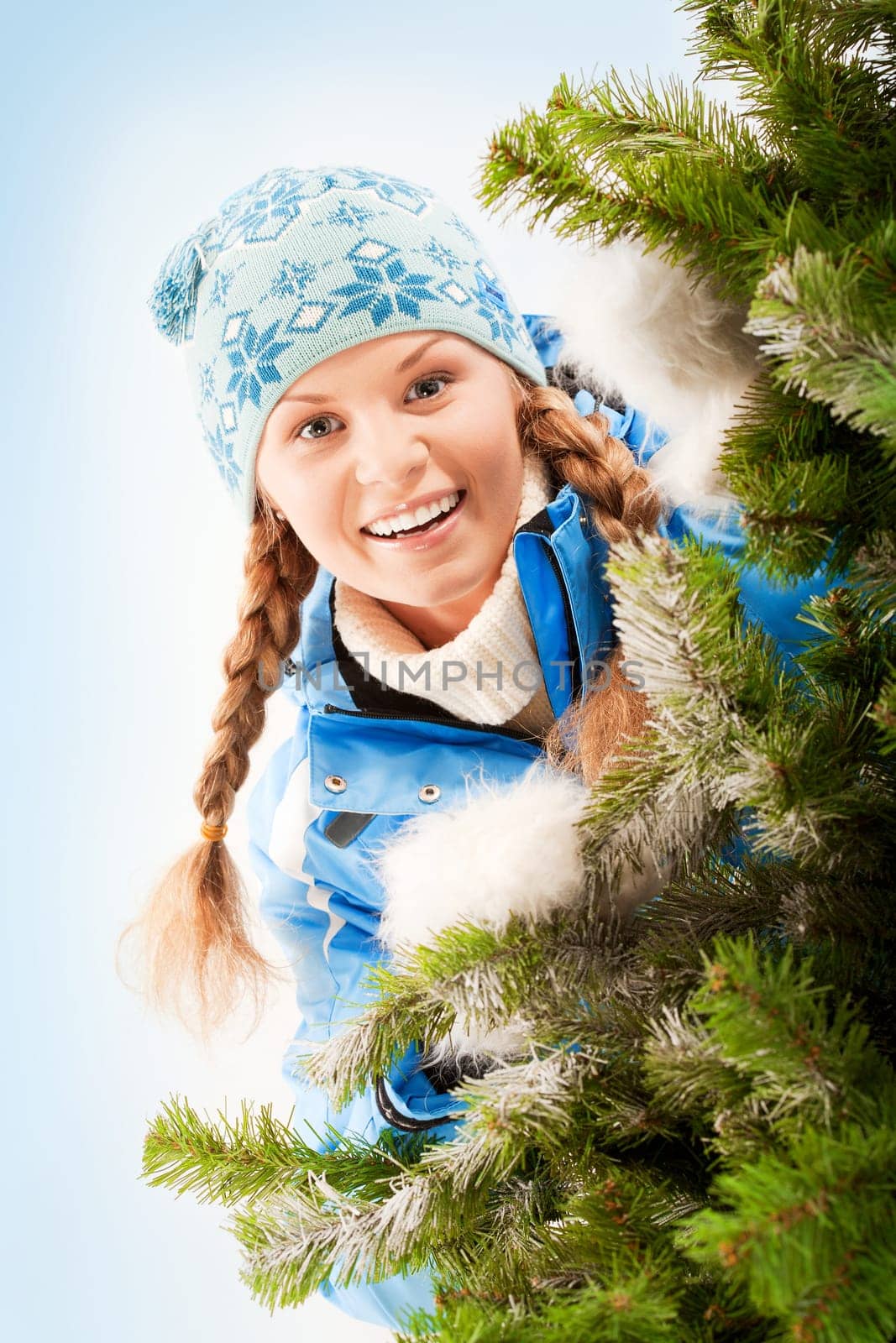 Portrait of young pretty woman peeping from Christmas tree