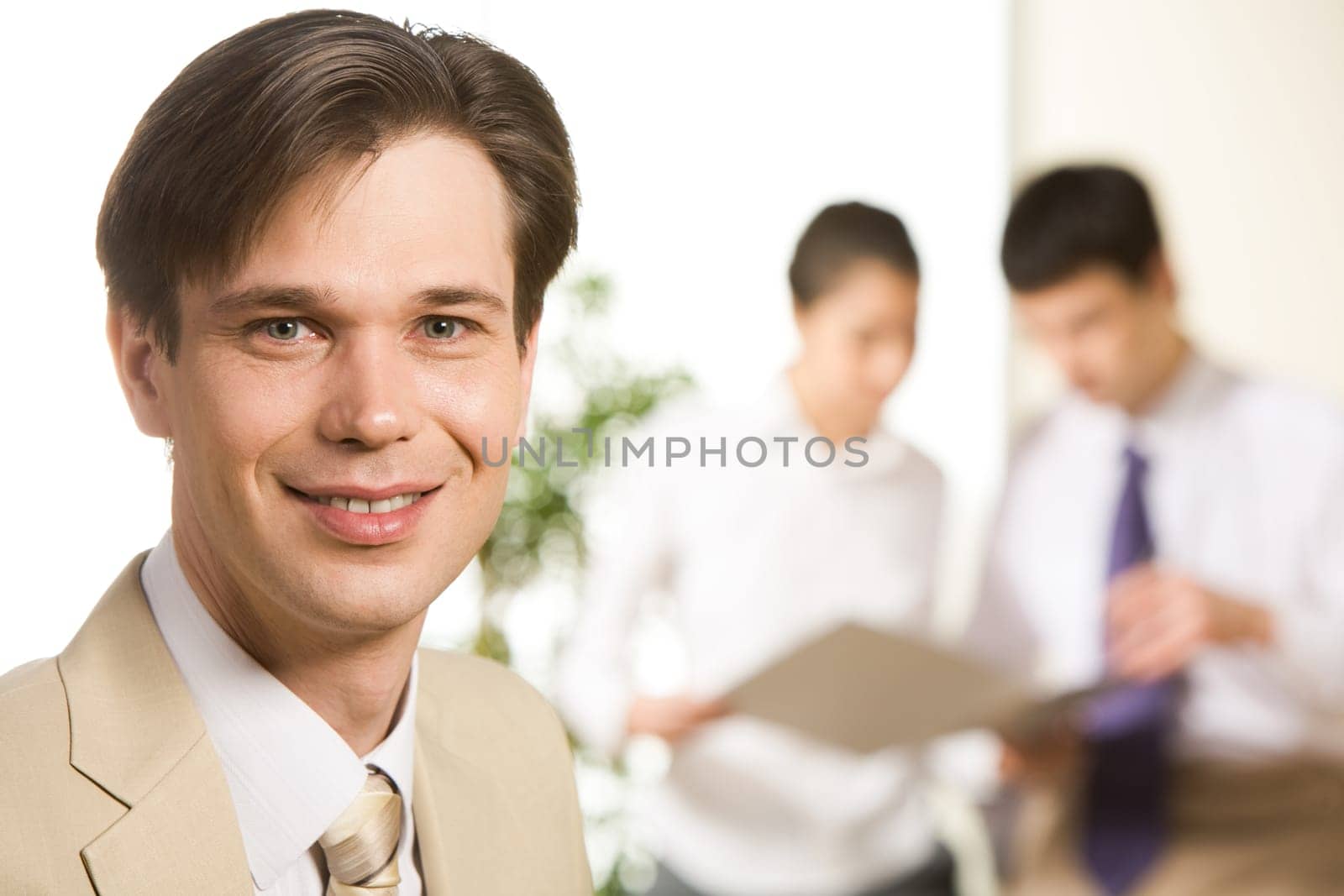 Portrait of confident businessman looking at camera on the background of coworkers