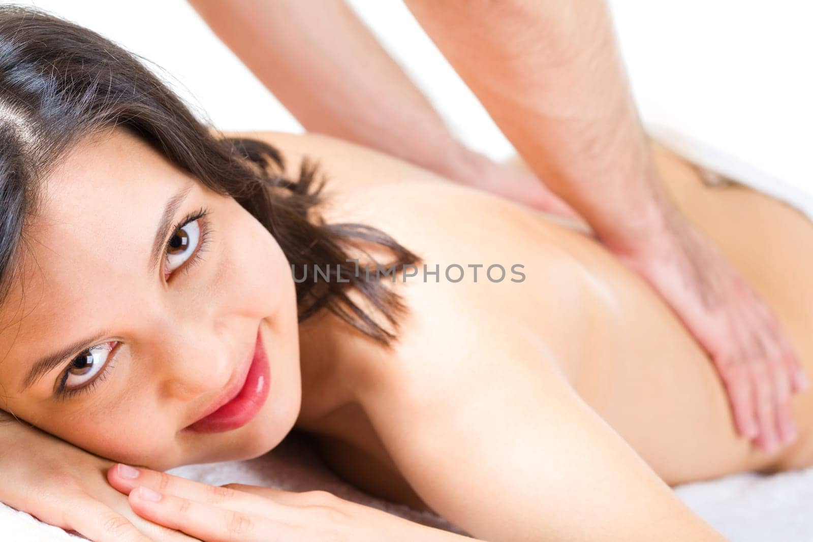 Young woman looks at camera while masseuse makes massage to her