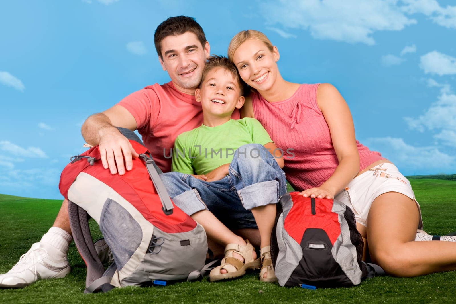 Portrait of family lying on grassland during rest over blue sky background