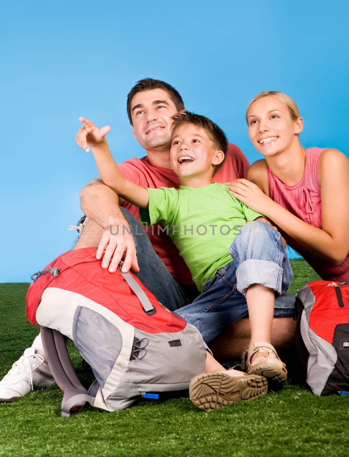 Portrait of family lying on grassland and looking where cute boy pointing during rest