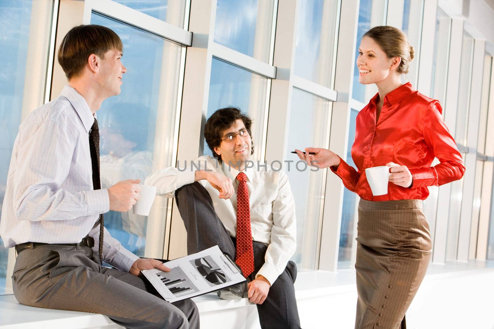 Portrait of businesswoman holding cup and explaining new project to businessmen