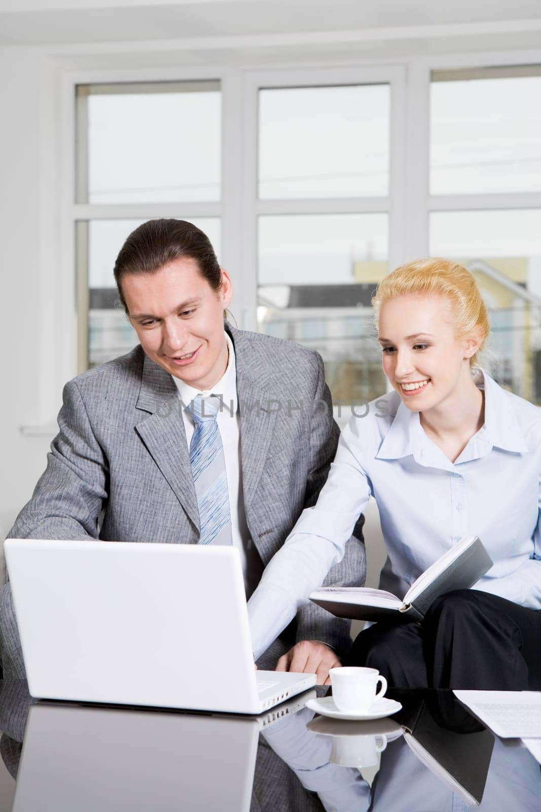 Portrait of friendly workteam looking at monitor of laptop and discussing something