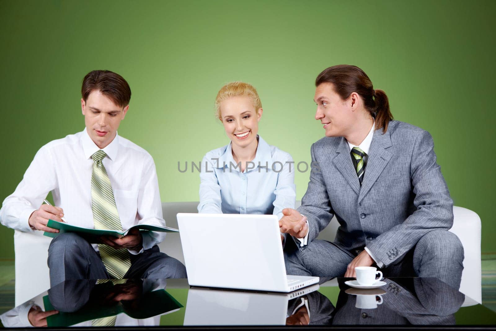 Portrait of businesspartners communicating at meeting with their colleague sitting near by