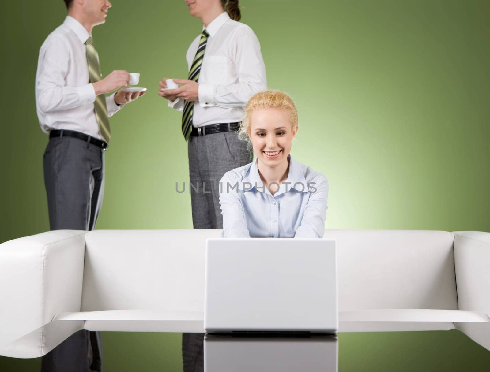 Image of pretty secretary working on laptop while two males drinking coffee and communicating at background