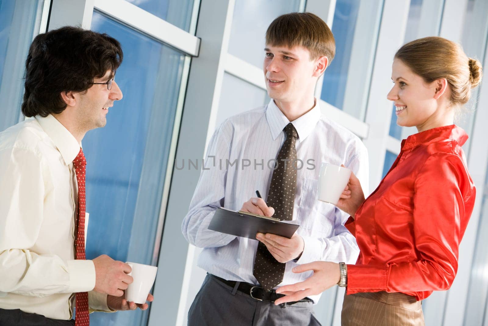 Image of three confident colleagues discussing a project during coffee break