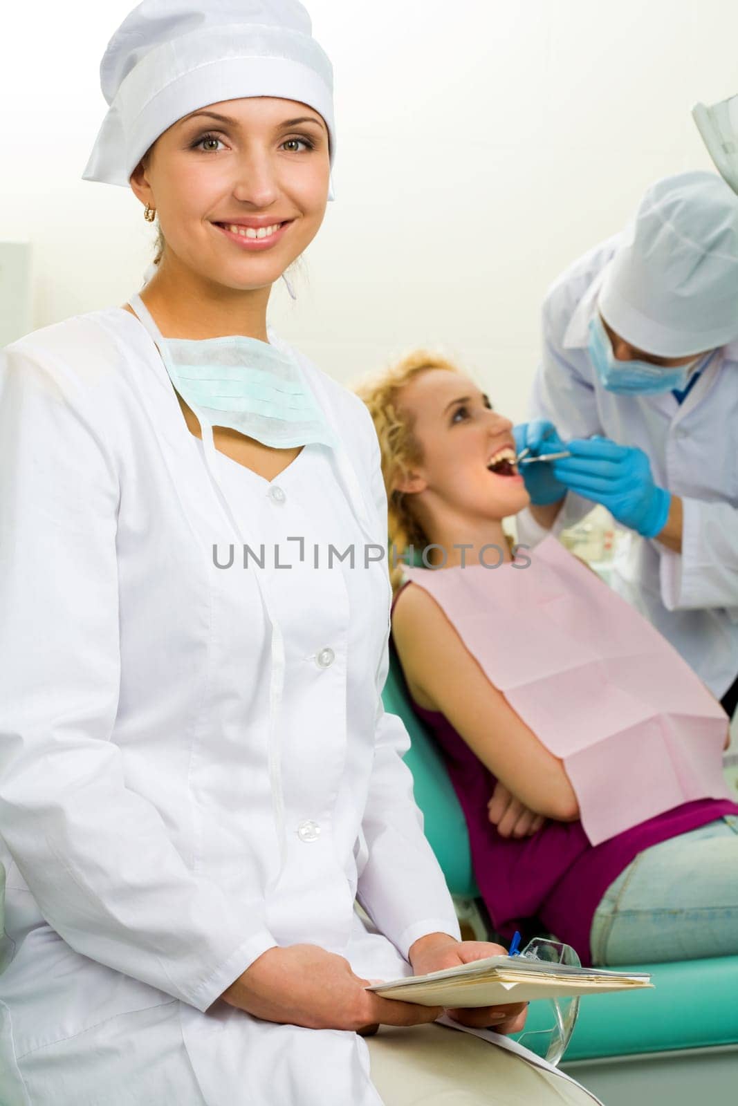 Portrait of young professional looking at camera on background of her colleague and patient
