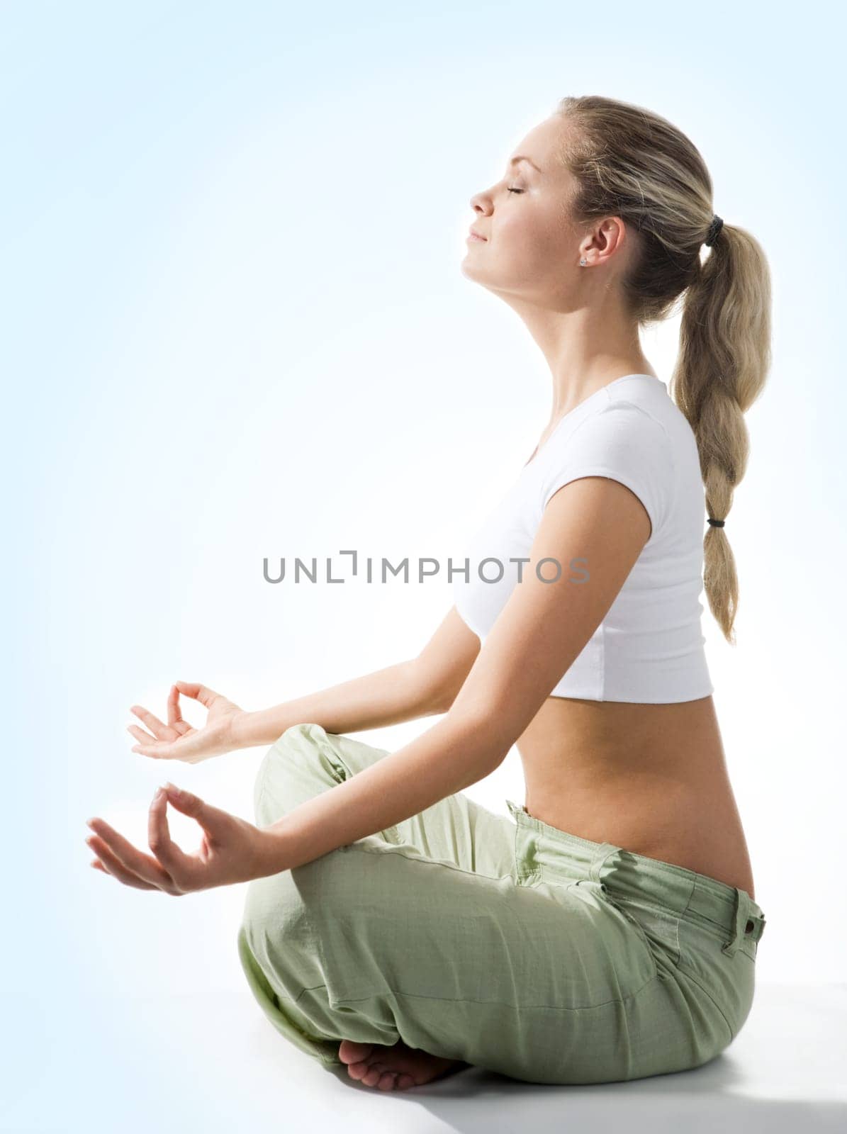Attractive woman meditating in pose of lotus on blue background