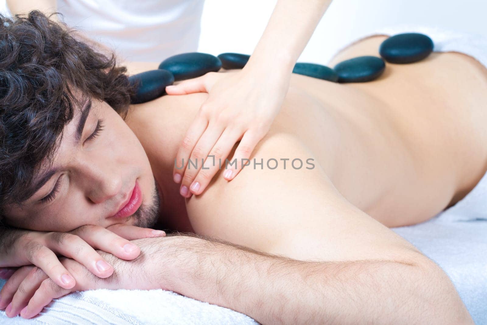 Image of man with spa stone on his back in the salon