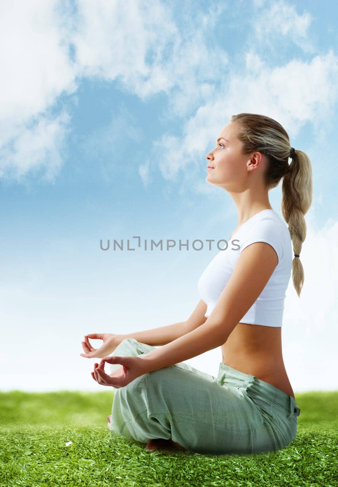 Portrait of young woman meditating in pose of lotus on green grass