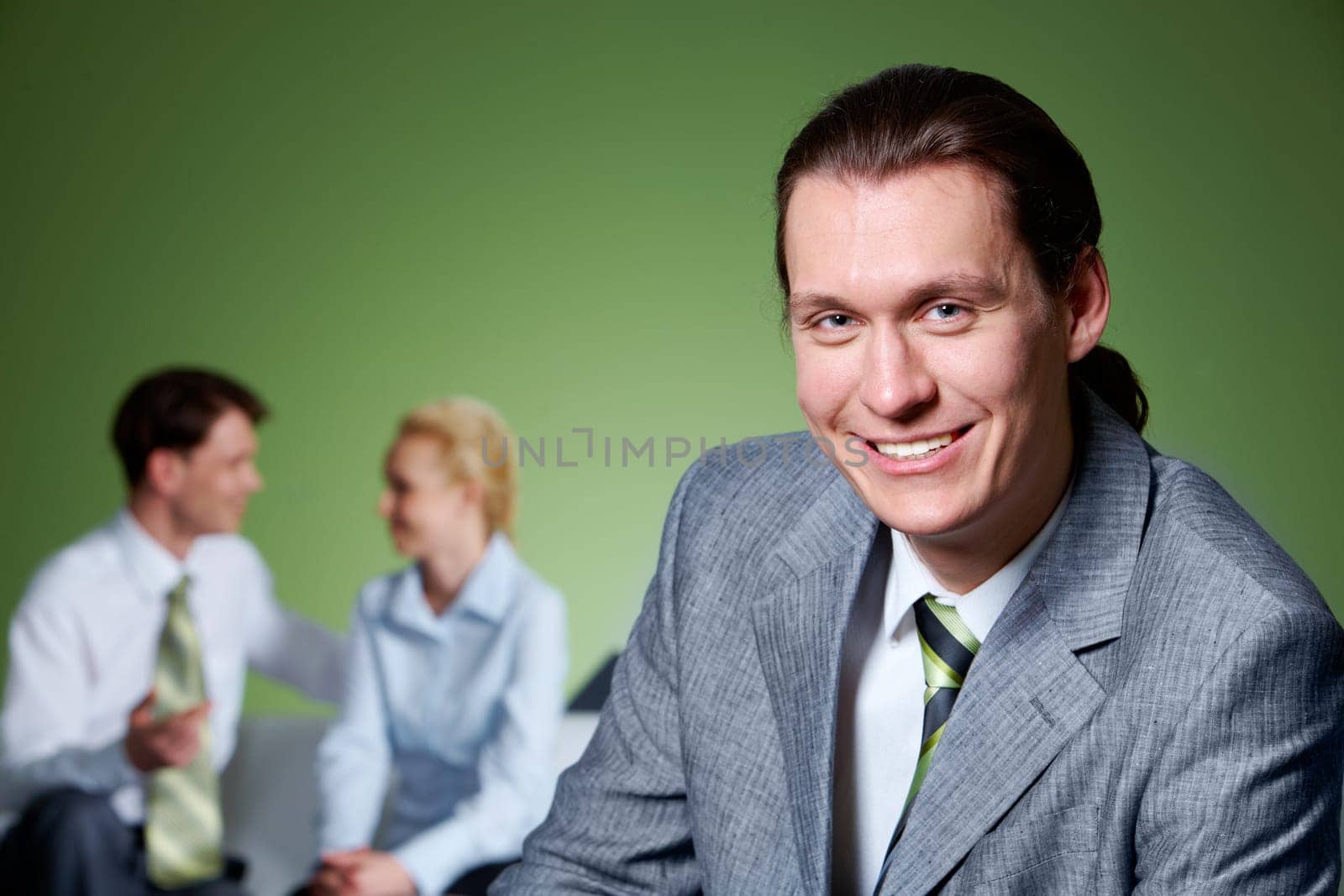 Portrait of people interacting with smiling businessman in front looking at camera
