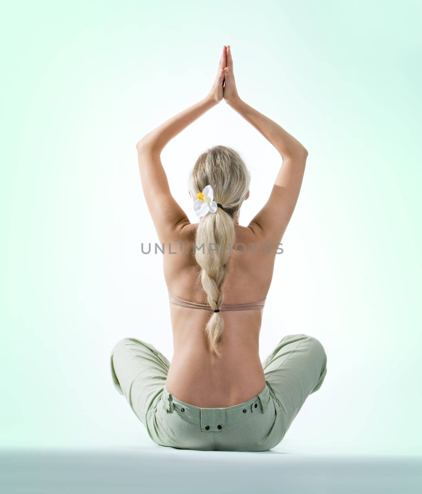 Back of beautiful woman sitting and keeping her hands raised with palms touching each other