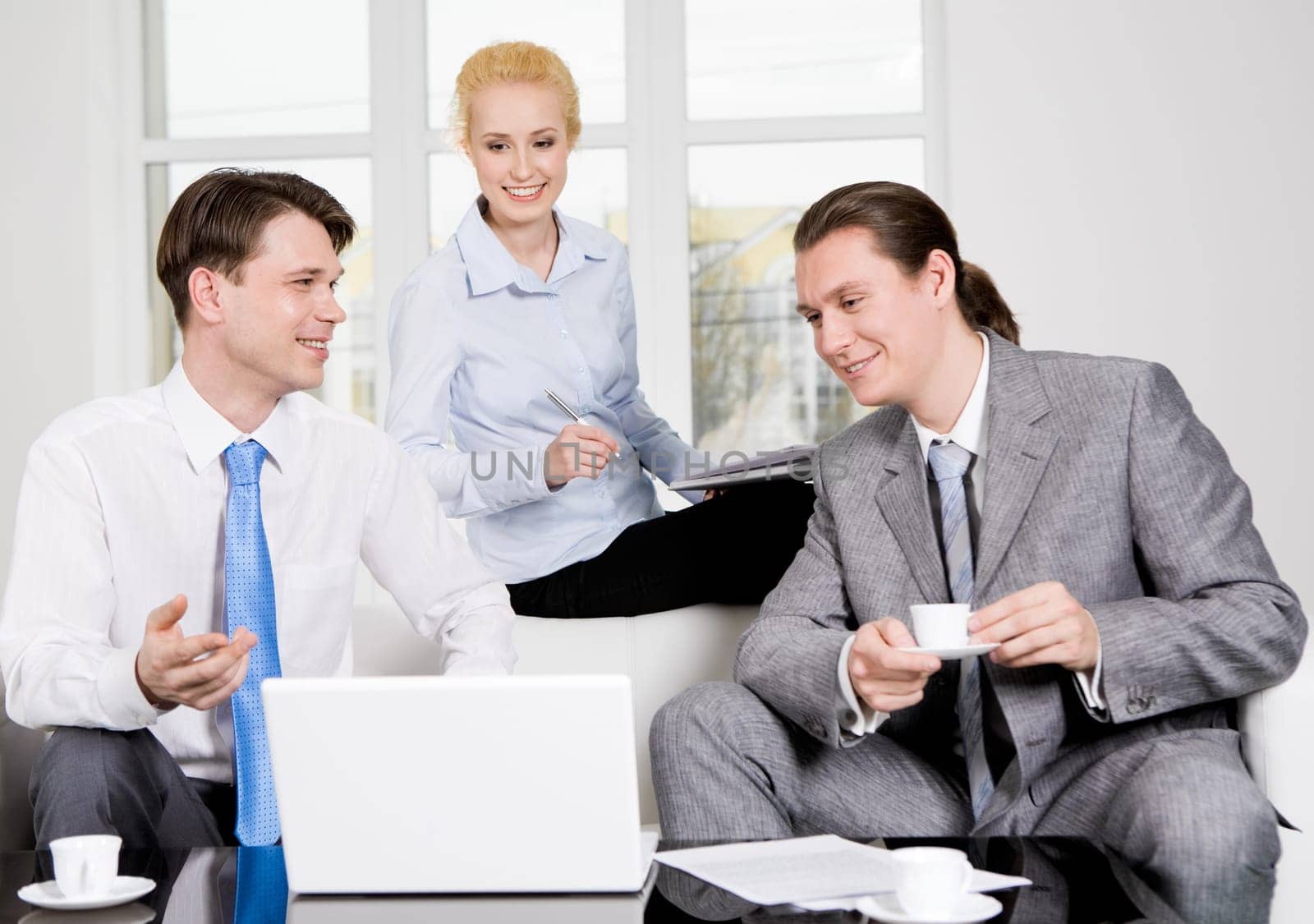 Portrait of successful co-workers sharing their ideas in office while looking at laptop monitor
