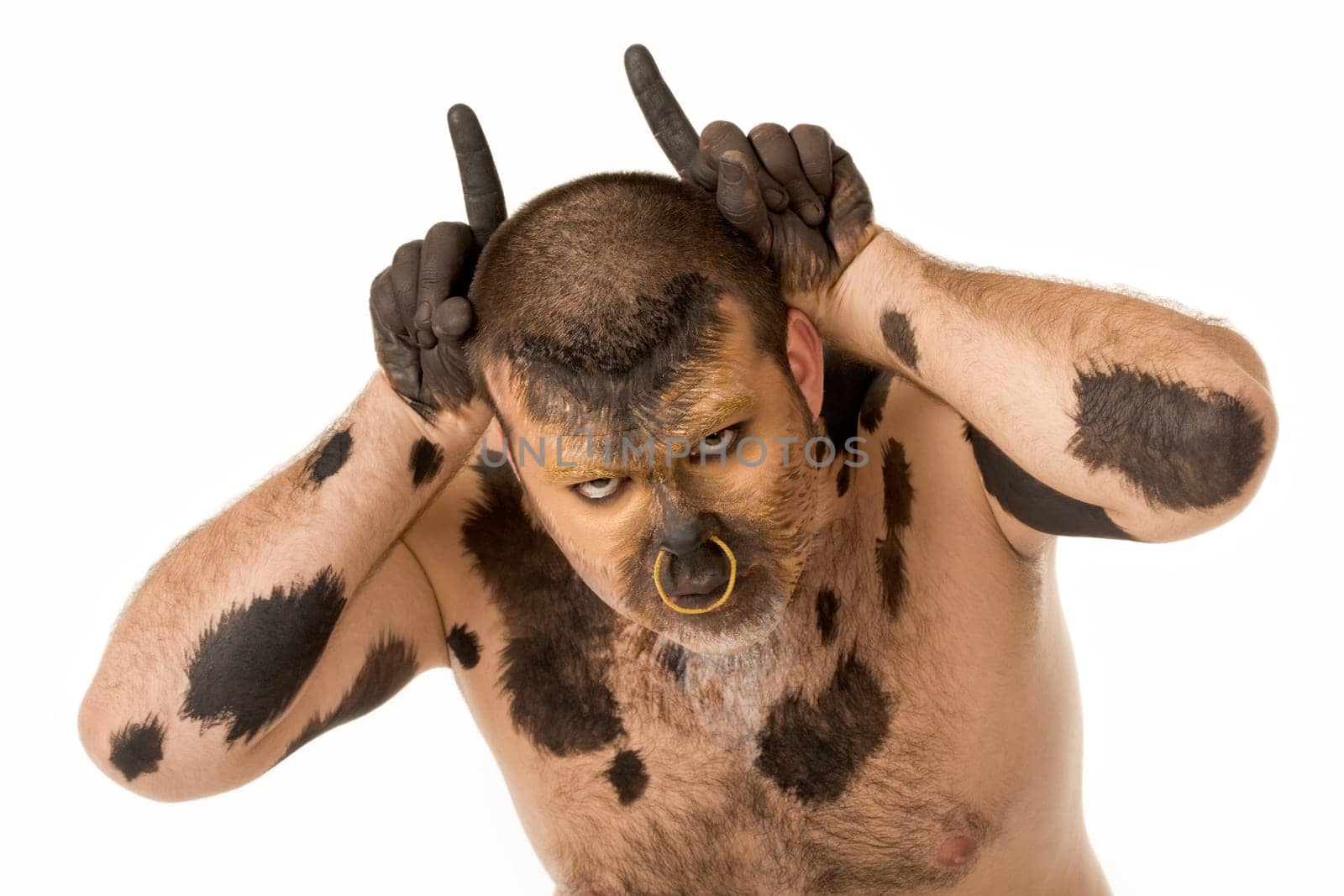 Portrait of bodypainted man imitating bull by pointing forefingers upwards by his head