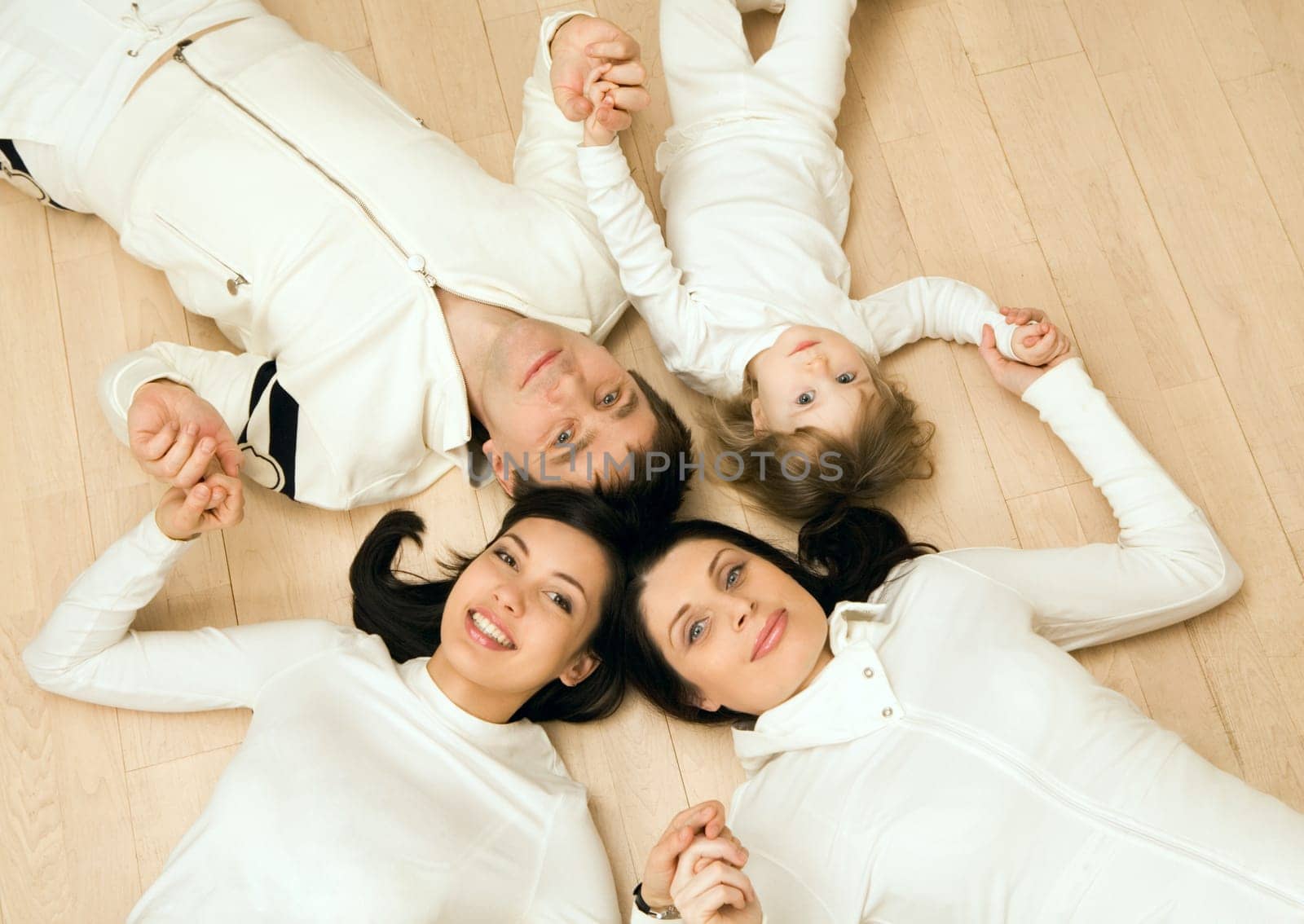 Above view of family members lying on the floor and holding each other by hands