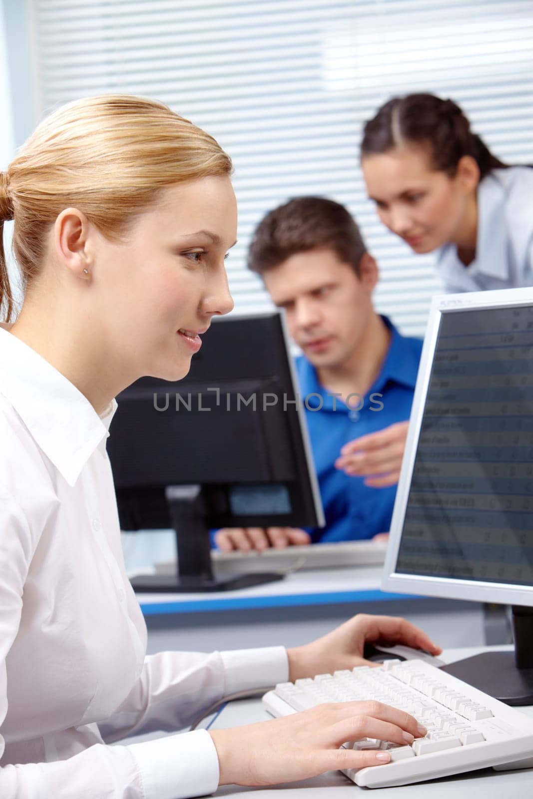 Image of secretary typing document on the background of working people
