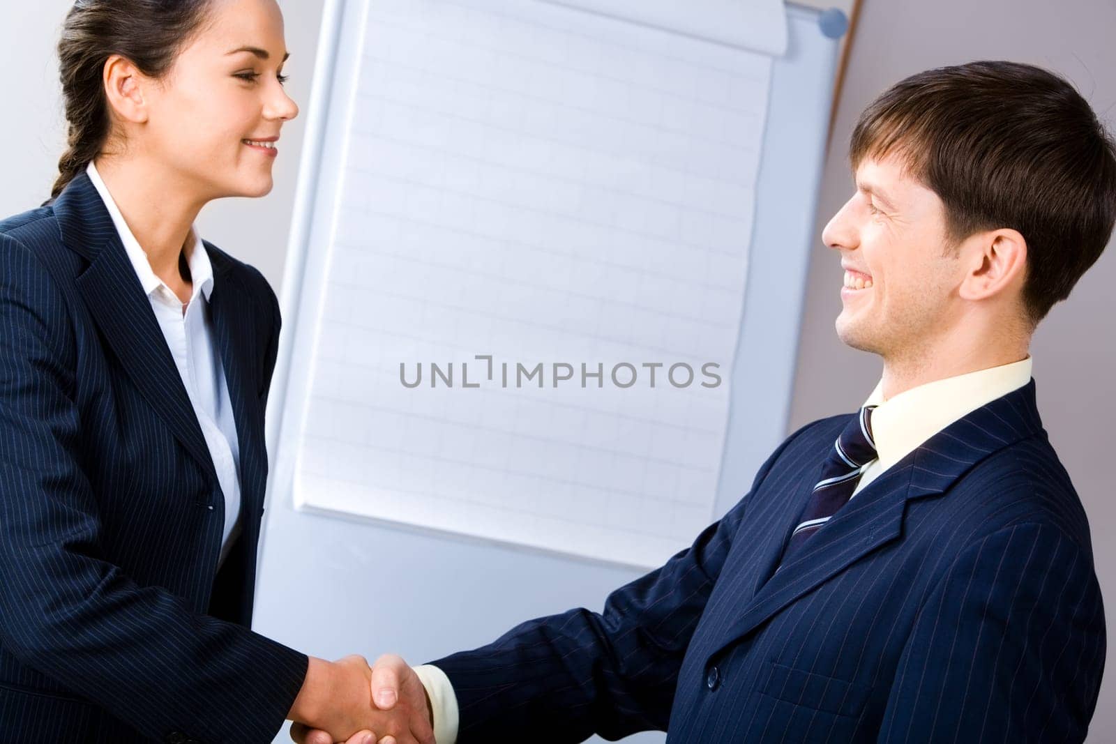 Business people shaking hands making an agreement on the background of whiteboard