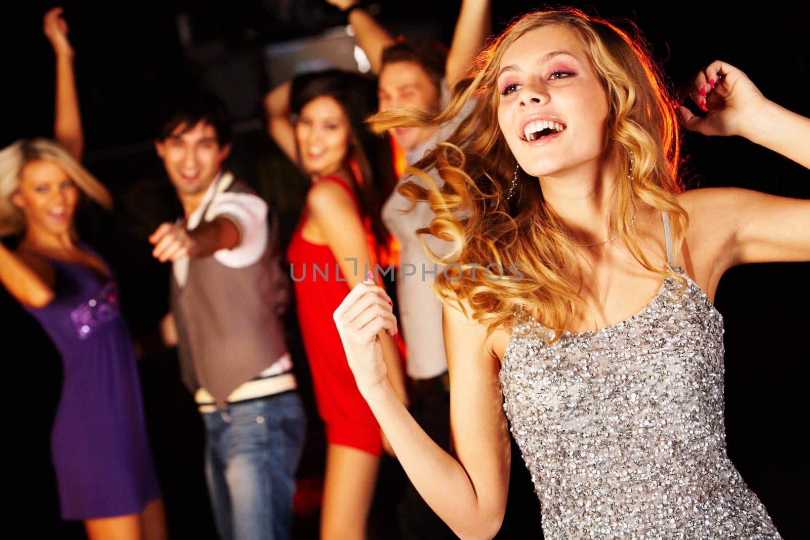 Portrait of joyous girl dancing at party on background of happy teens