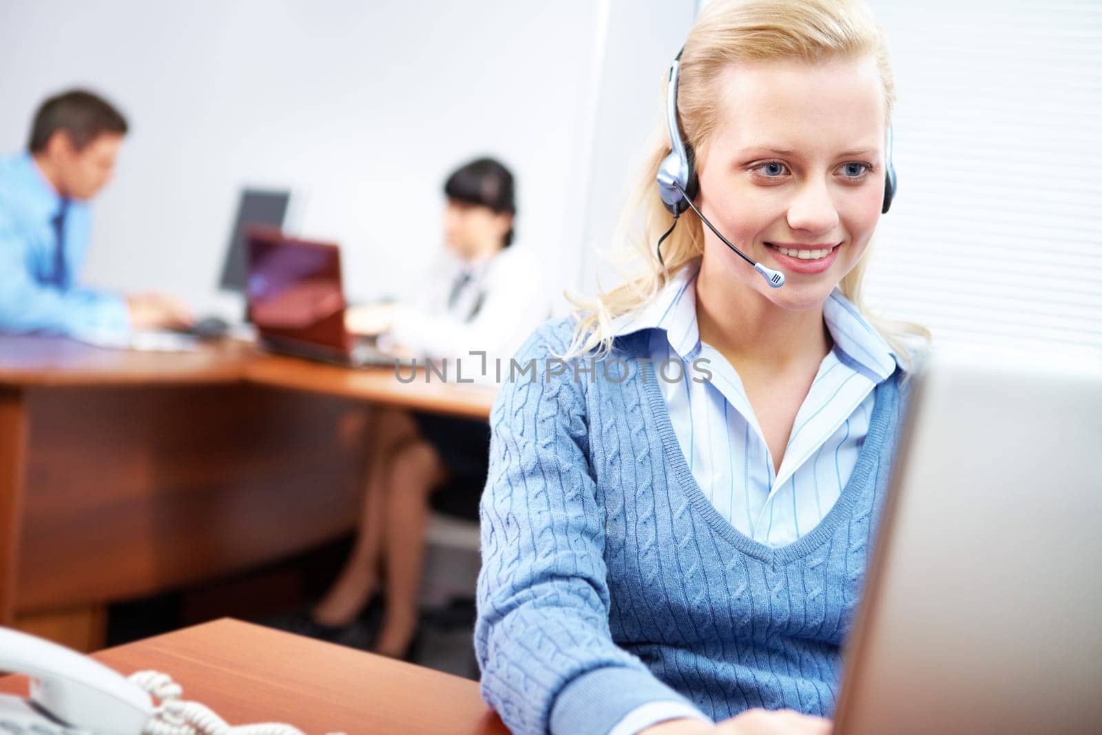 A young businesswoman sitting in headset at the laptop