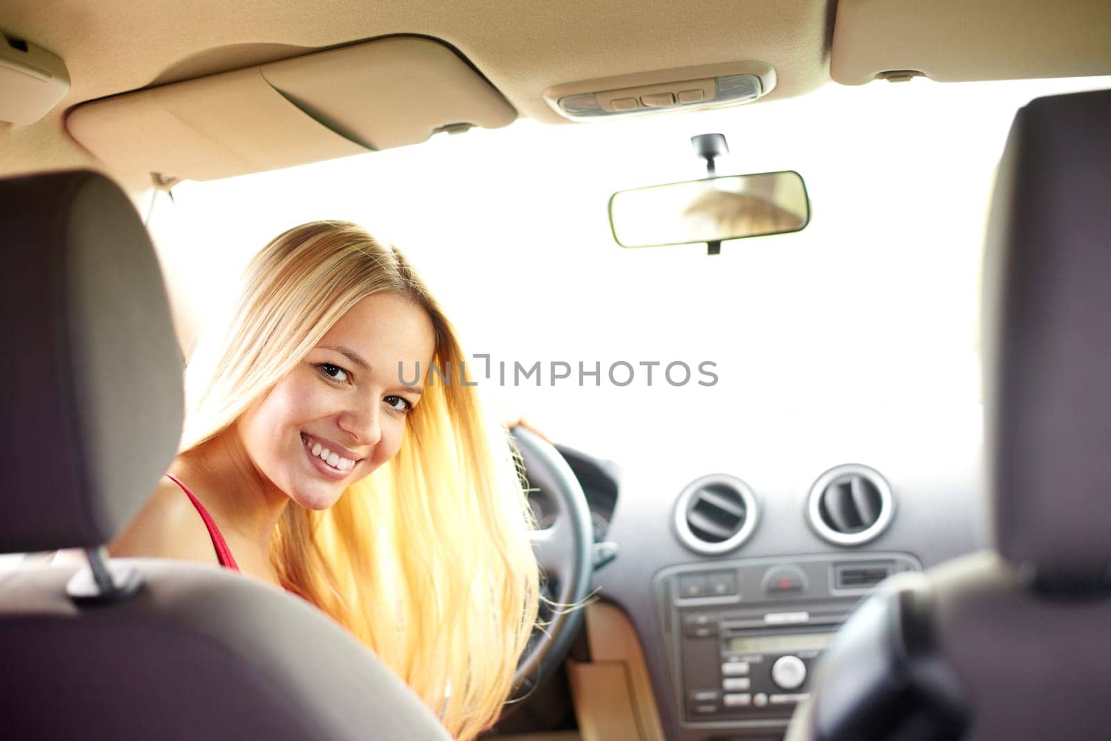 Happy blond woman looking at camera in the car
