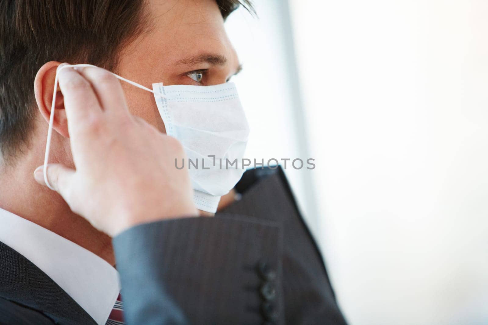 Portrait of businessman putting protective mask on his face