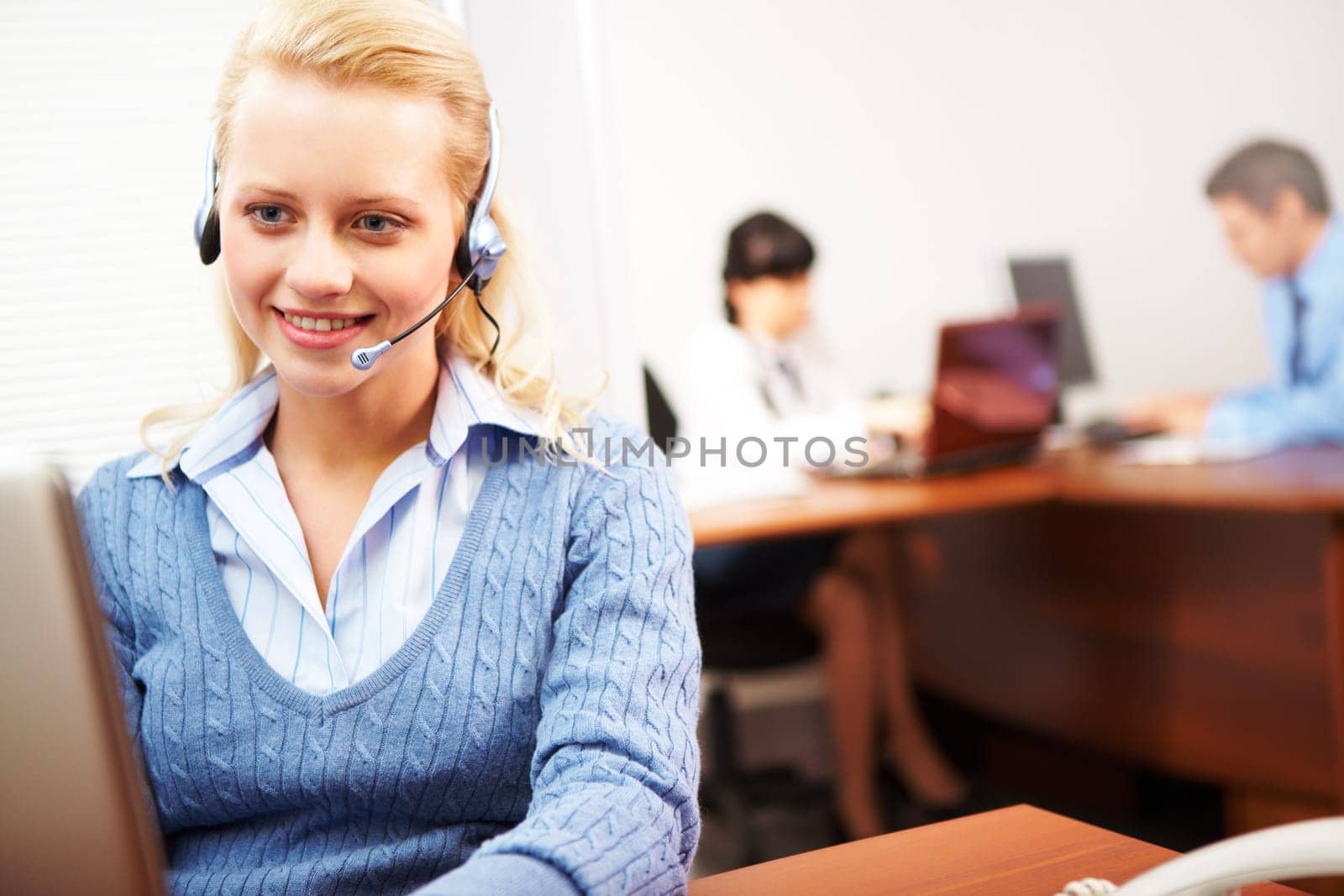 Pretty secretary speaking on headphone in the office