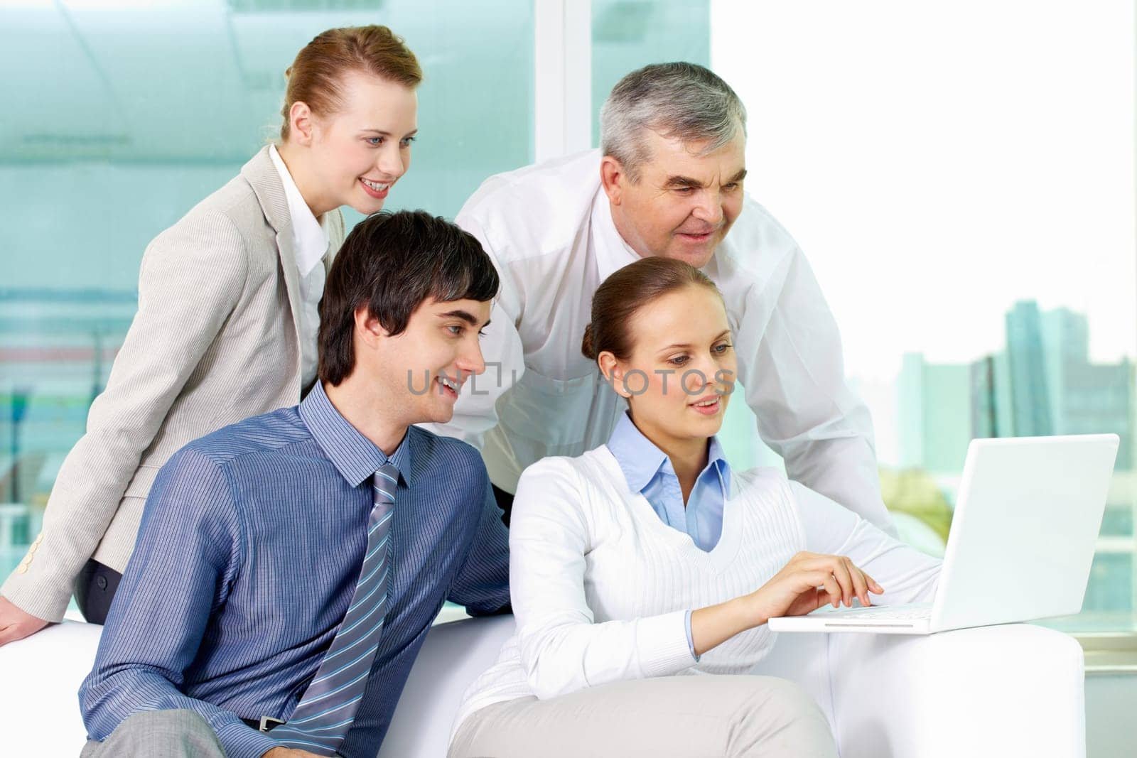 Portrait of several colleagues looking at laptop screen in office