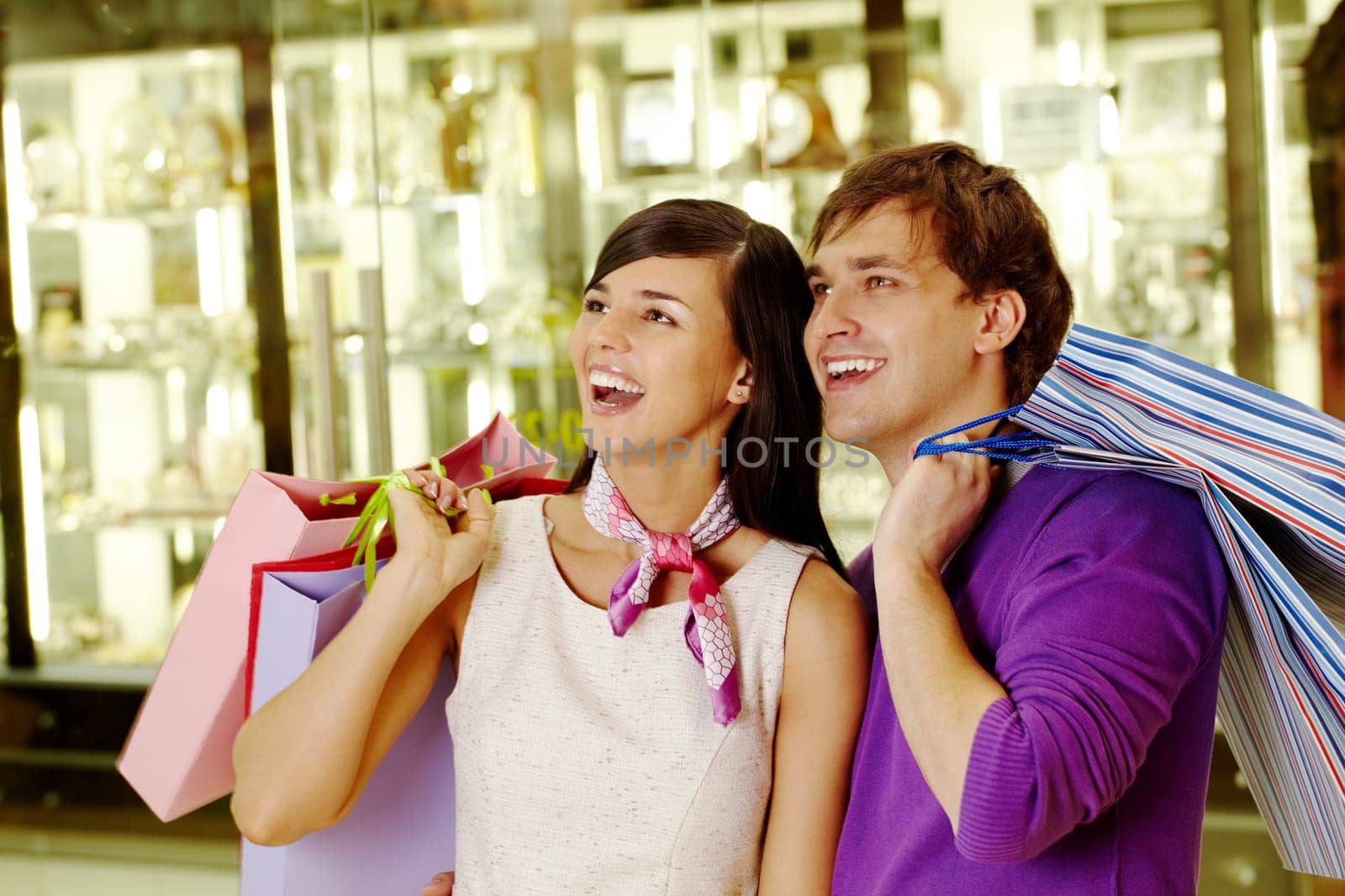 Portrait of joyful husband and wife looking at some goods in the mall