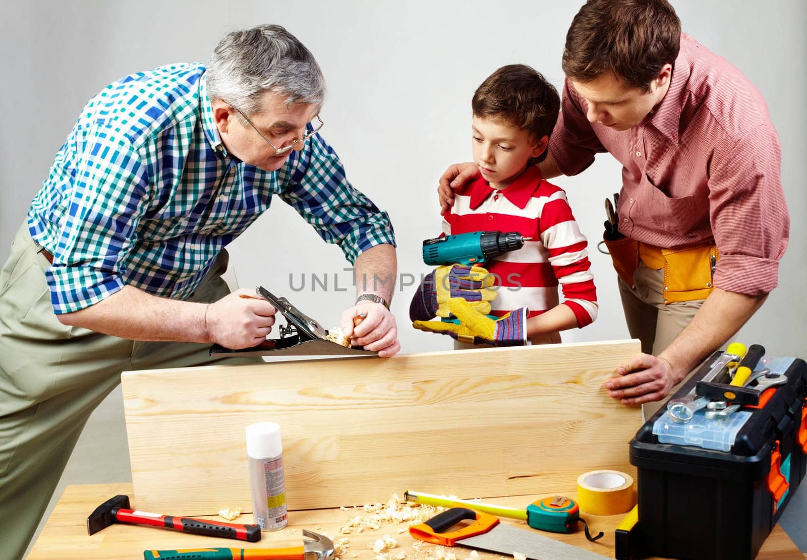 A grandfather and a father teaching a boy to work with plane