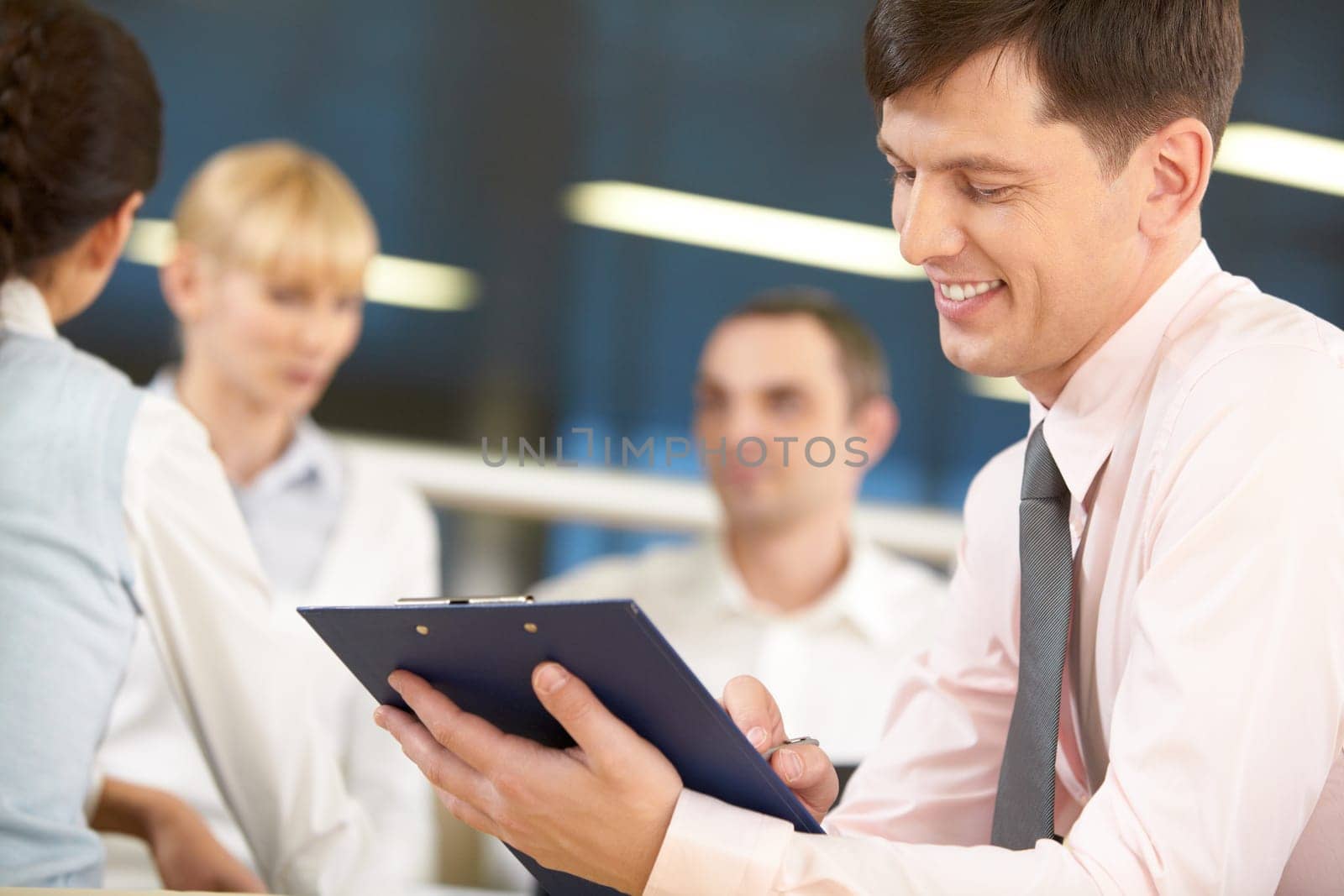 A chief manager signing a project and smiling against his three colleagues