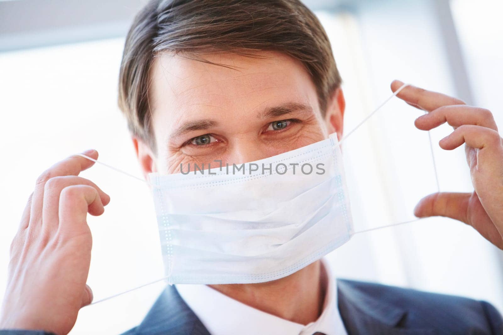 Portrait of businessman holding protective mask before himself