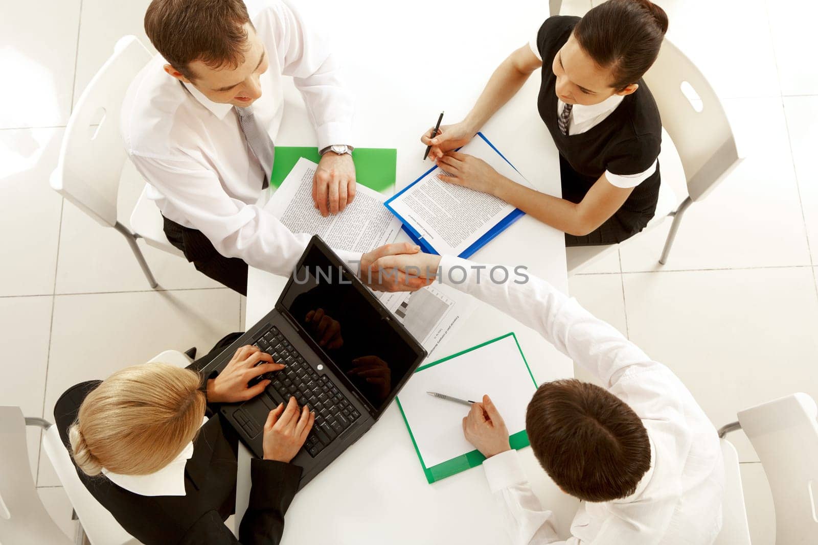 View from above of happy partners shaking hands at meeting