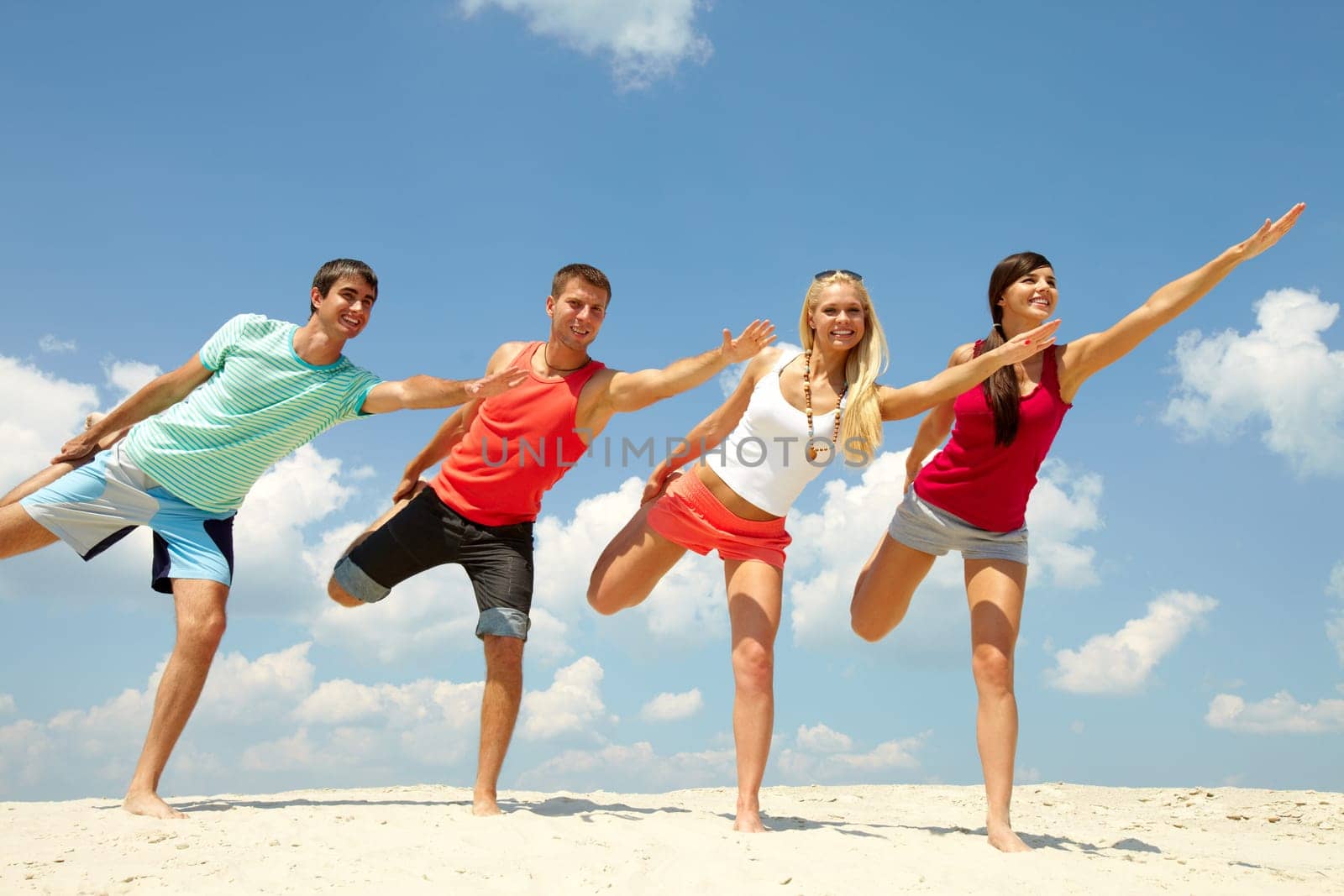 Four happy friends doing exercise on the beach