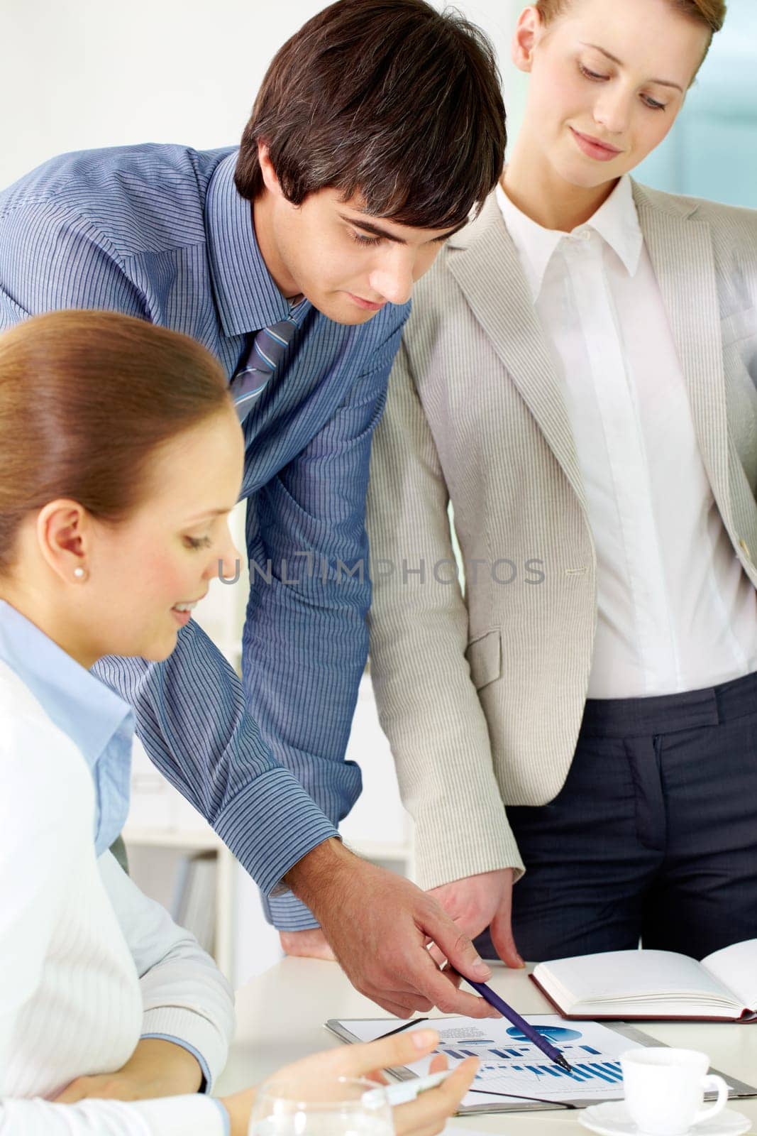 Portrait of confident man pointing at document surrounded by females in office