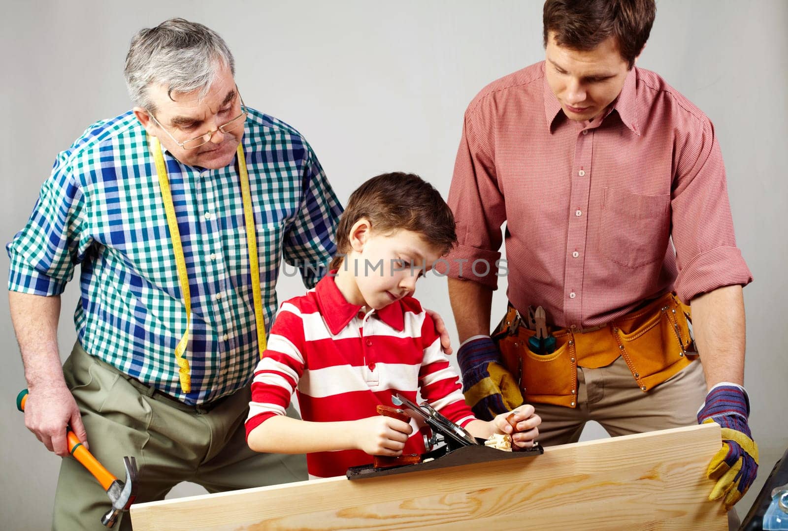 A boy working with plane under his father and grandpas supervision