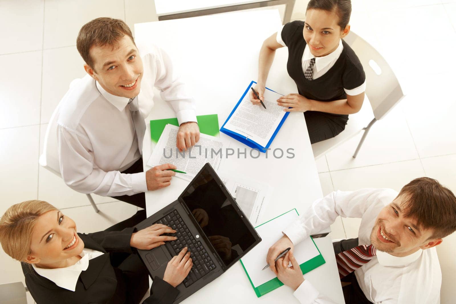Several white collar workers looking upwards at camera from their workplaces