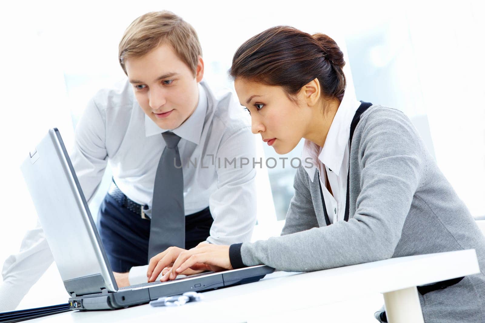 Successful businessman and his pretty colleague looking at monitor of computer